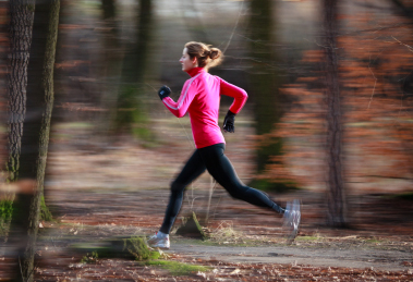 Young woman running outdoors in a city park on a cold fall/winte