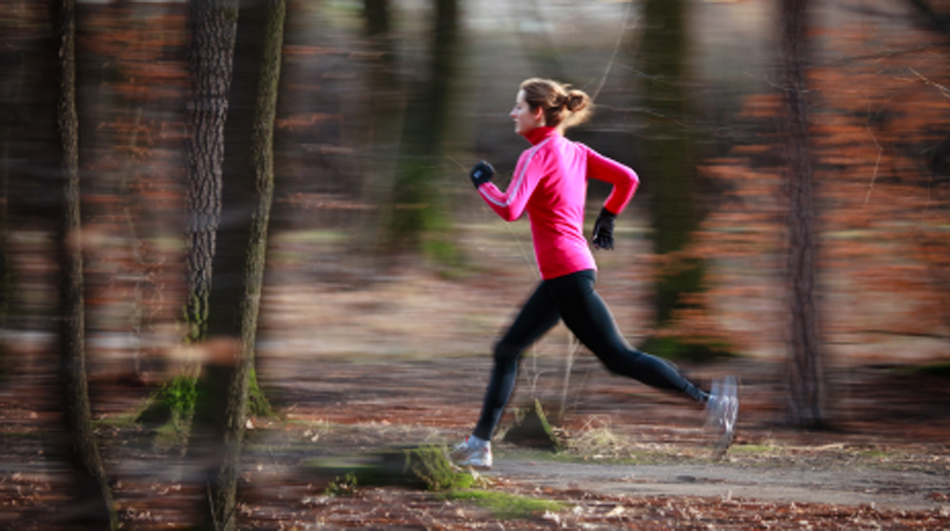 Young woman running outdoors in a city park on a cold fall/winte